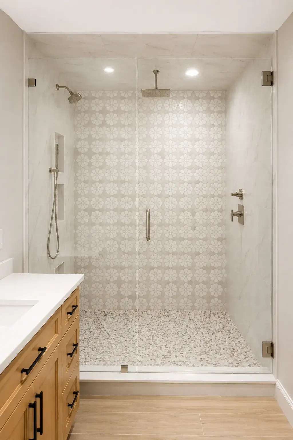 Walk-in shower with patterned wall tile, a pebble floor, and a frameless glass door