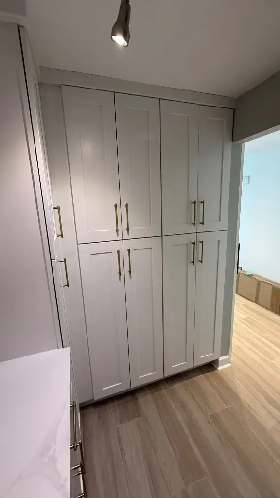 Floor-to-ceiling pantry cabinets with brass pulls