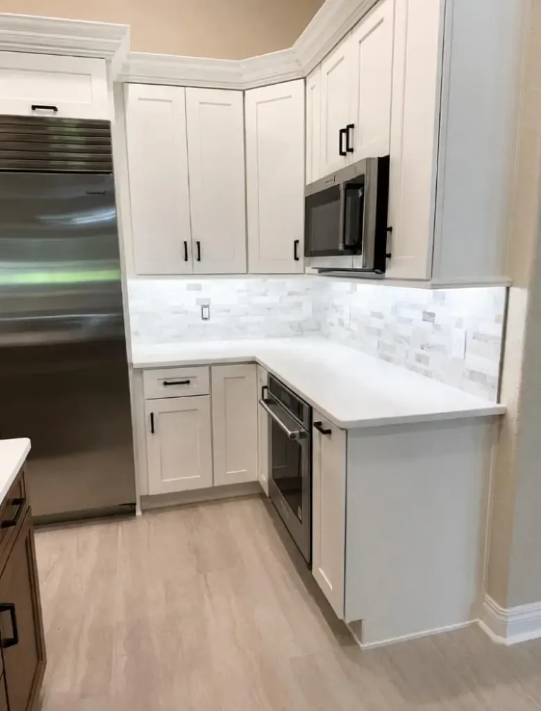 White shaker kitchen cabinets with a stone counter and backsplash