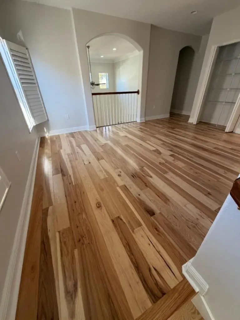 Wide-plank hickory hardwood floor in an upstairs hall with arched openings