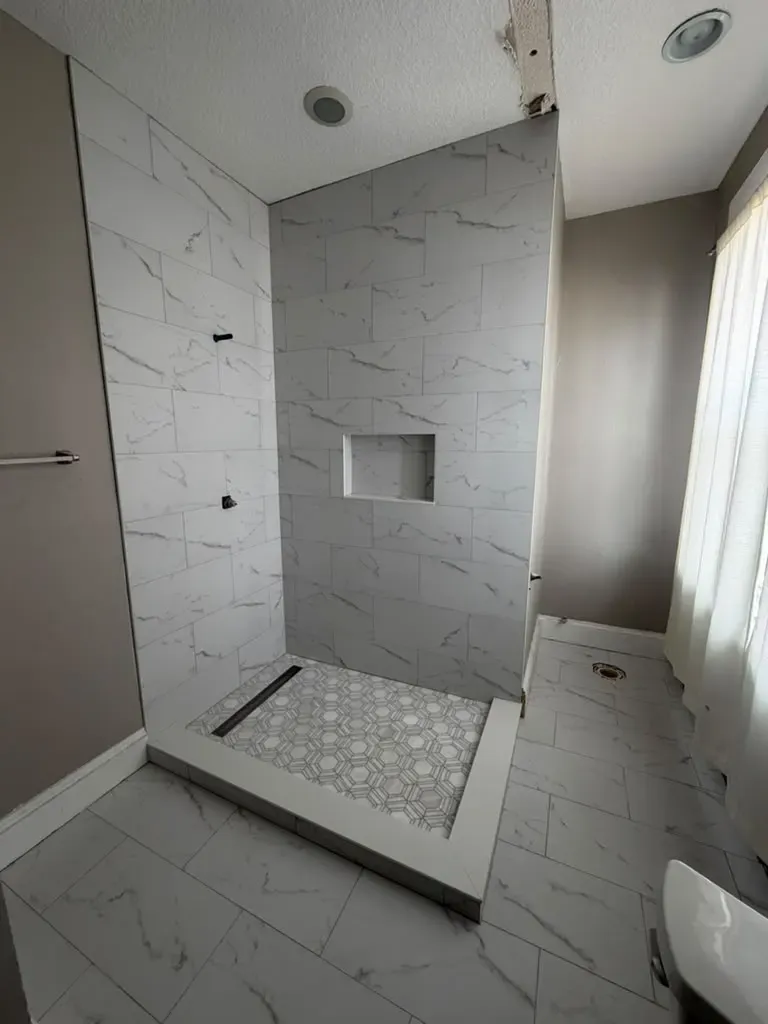 Walk-in shower with a linear drain along the back wall and large-format tile Walk-in shower with a linear drain along the back wall and large-format tile