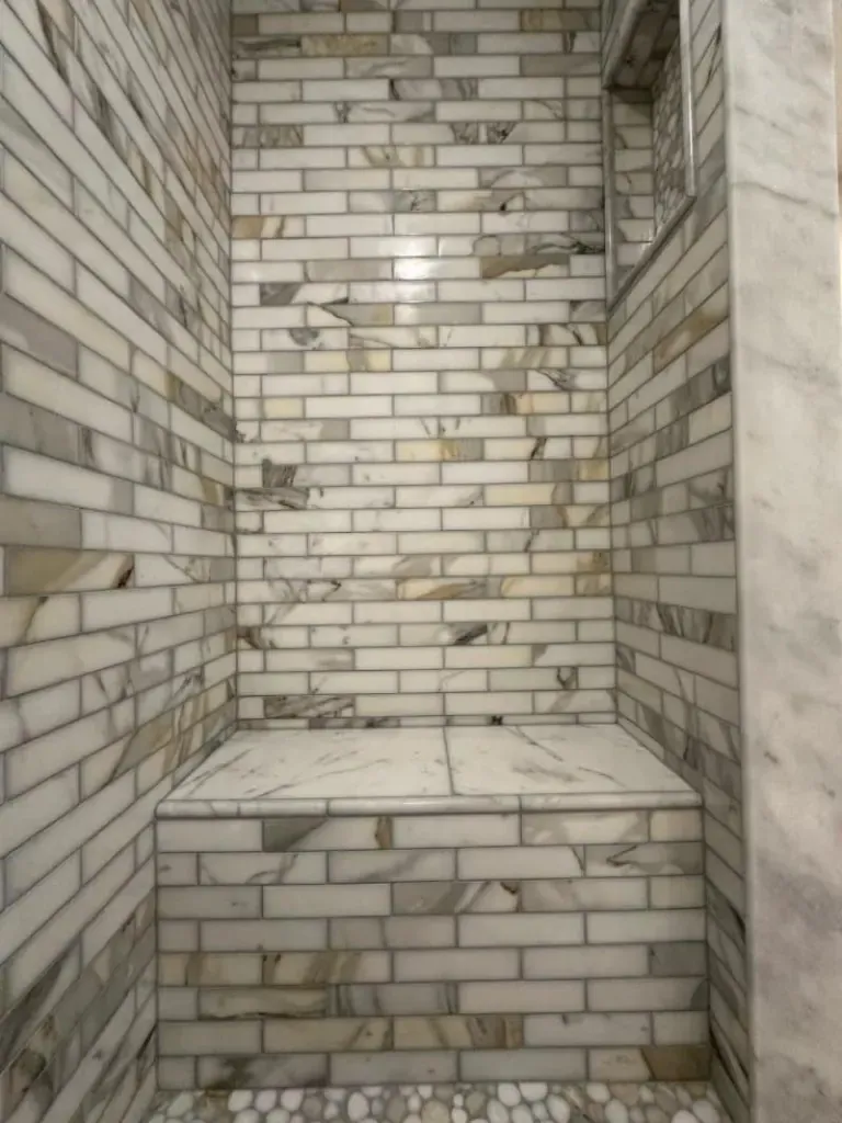 Marble-look shower with a built-in bench and a glass enclosure Marble-look shower with a built-in bench and a glass enclosure