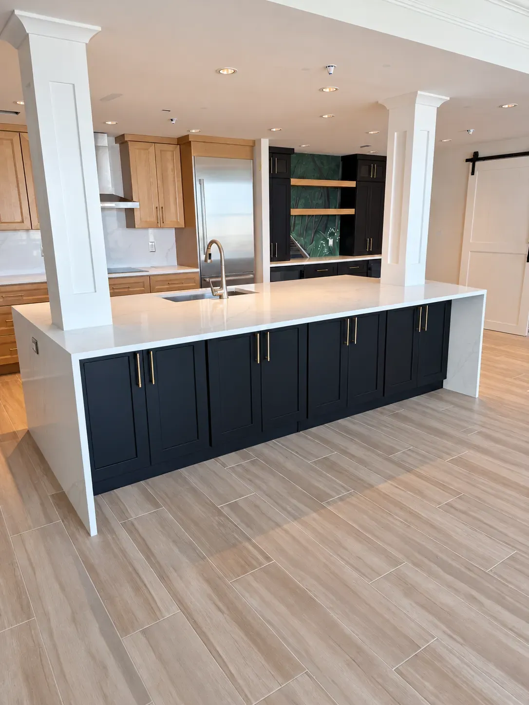 Navy shaker island with brass pulls and a white waterfall counter between two square columns Navy shaker island with brass pulls and a white waterfall counter between two square columns